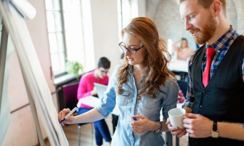 Zwei Mitarbeitende arbeiten konzentriert an einem Flipchart während eines Teamcoachings. Das Bild symbolisiert Führungskräfteentwicklung, Kommunikation und betriebliche Gesundheitsförderung durch das Gesundheitsteam Liebe.